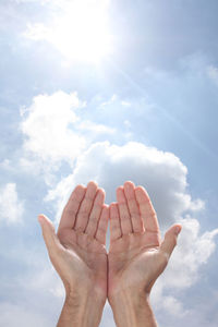 Low angle view of human hand against sky