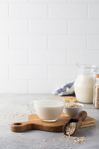 Oatmeal vegetable milk in a mug on the table with oatmeal in a bowl.