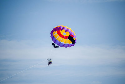 Low angle view of parascending against blue sky