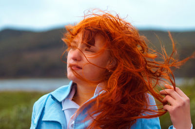 Close-up of young woman with tousled hair at lakeshore