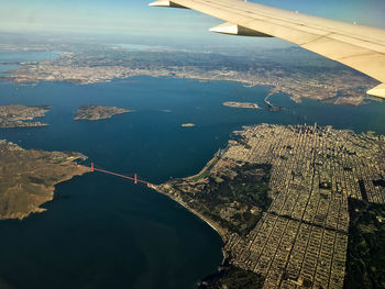 Aerial view of airplane wing over landscape against sky