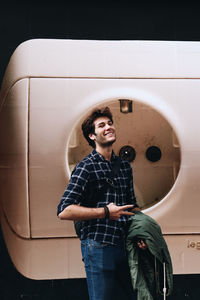 Portrait of young man standing against wall