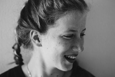 Close-up of smiling woman looking away against wall