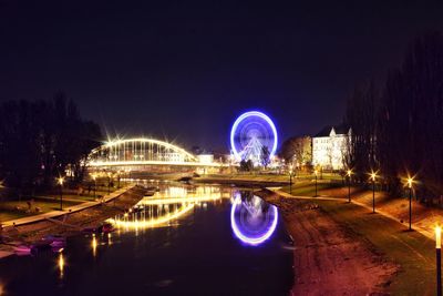 Illuminated bridge over river in city against sky at night