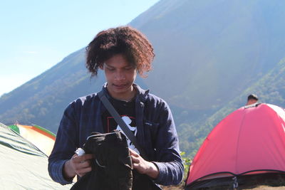 Portrait of young man holding umbrella against mountains