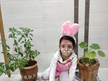 Portrait of smiling girl standing by potted plants