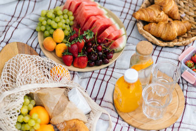 Fresh fruits and drinks on a picnic blanket.