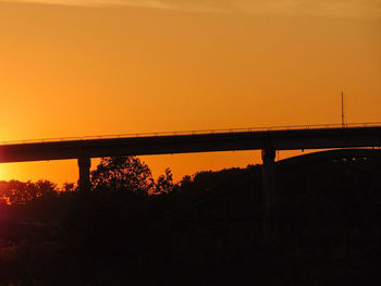 Silhouette bridge against orange sky