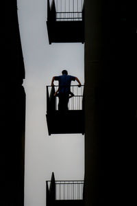 Low angle view of silhouette friends standing in balcony against sky
