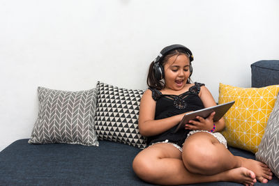 Young woman using phone while sitting on sofa at home