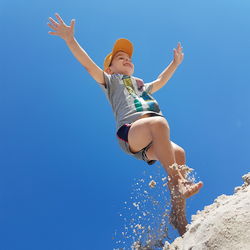 Low angle view of girl against blue sky