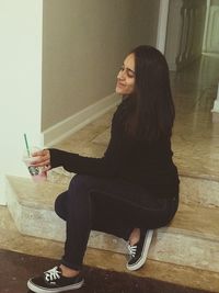 Side view of young woman sitting on floor at home