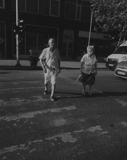 Rear view of man and woman walking on street at night