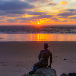 Rear view of sea against sky during sunset mermaid statue at folkestone 