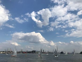 Sailboats in sea against cloudy sky