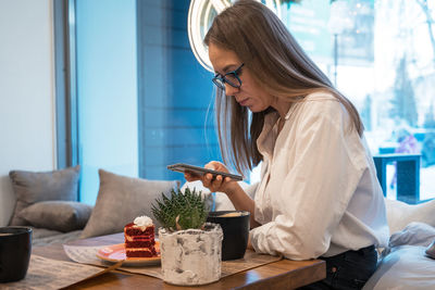 Young woman using mobile phone while sitting at home