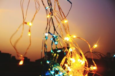 Close-up of illuminated christmas lights against sky at night