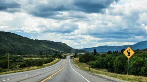 Road by mountains against sky