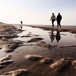 Three people walking on beach