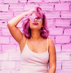 Portrait of beautiful woman standing against pink wall