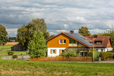 Trees and houses on field against sky