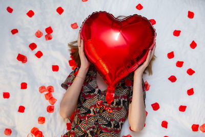 High angle view of woman holding heart shape on bed