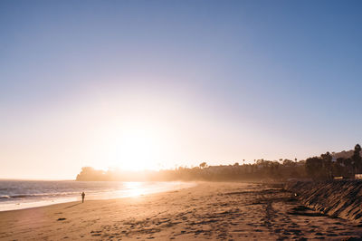 Scenic view of beach against clear sky during sunset