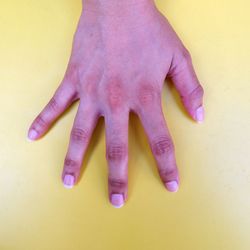 Close-up of human hand against colored background