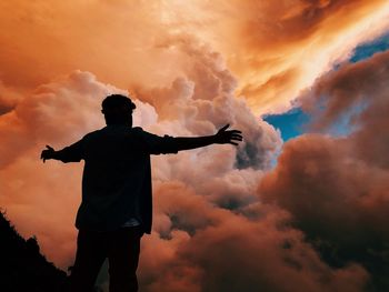 Rear view of silhouette man standing against sky during sunset