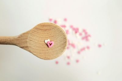 Directly above view of heart shape candies in wooden spoon on white background