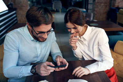 Cheerful colleagues looking at mobile phone