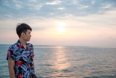 Teenage girl looking at sea against sky during sunset