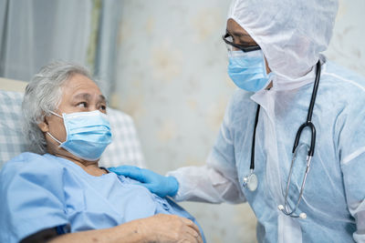 Doctor wearing protective suit consoling patient at hospital