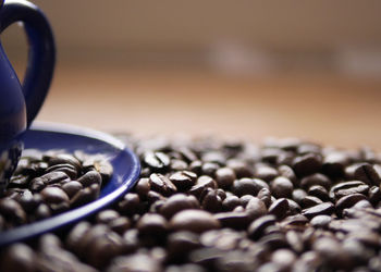 Close-up of coffee beans with cup and saucer on table