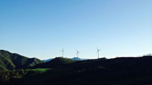 Wind turbines on landscape against clear sky