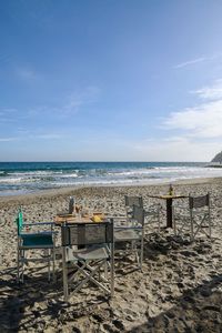 Empty beach bar with tables and chairs on the sand and the sea in the background, liguria