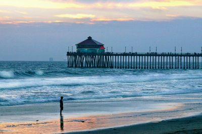 View of calm beach against cloudy sky