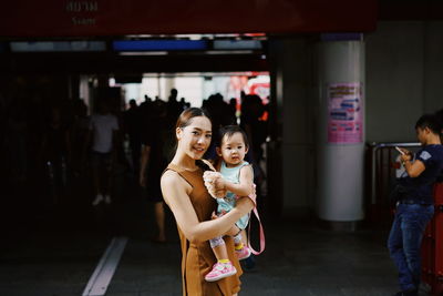 Portrait of woman carrying son while standing outdoors