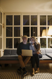Senior couple using laptop on couch at home at night