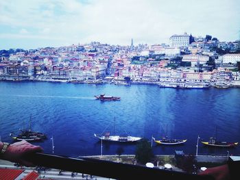 Boats in sea by cityscape against sky