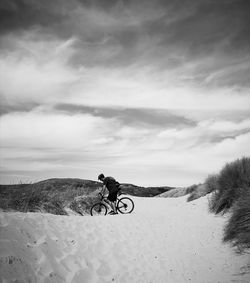 Cyclist riding on sand dunes at deganwy, conway. 