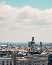 Aerial view of cityscape against cloudy sky during sunny day