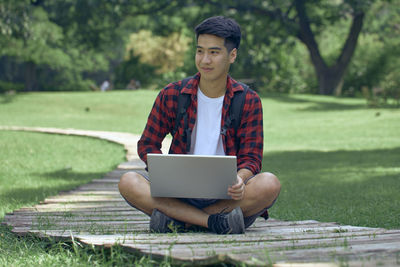 Young man using mobile phone while sitting on grass