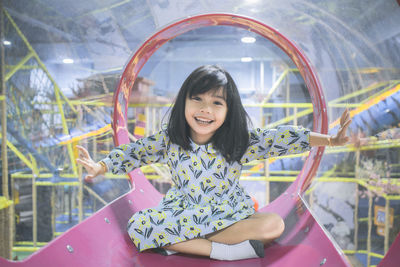 Portrait of smiling innocent girl sitting in slide