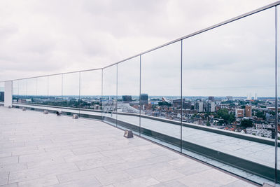 View from glass protected rooftop against cloudy sky and skyline