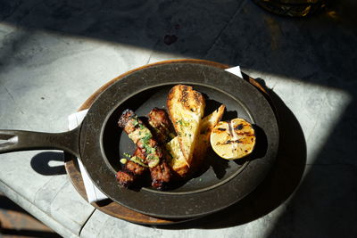 Light shining on a plate of sausage, toast and lemon.