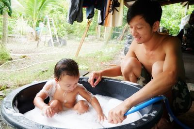 Young man looking at son bathing in tub