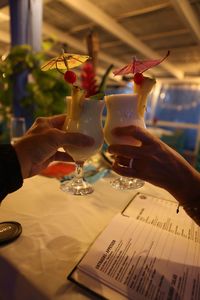 Midsection of people holding wine glass on table