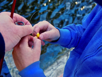 Son helping father in attaching corns to fishing hook