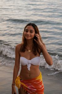 Portrait of beautiful young woman standing on beach